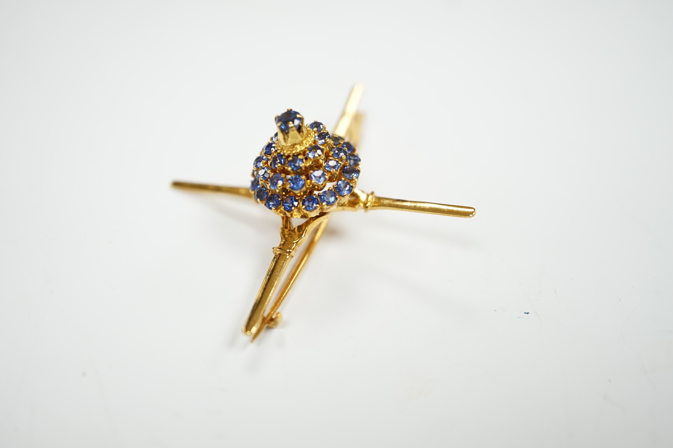 A yellow metal and sapphire cluster set brooch, of 'X' form with raised central motif, 45mm, gross weight 6.2 grams.
